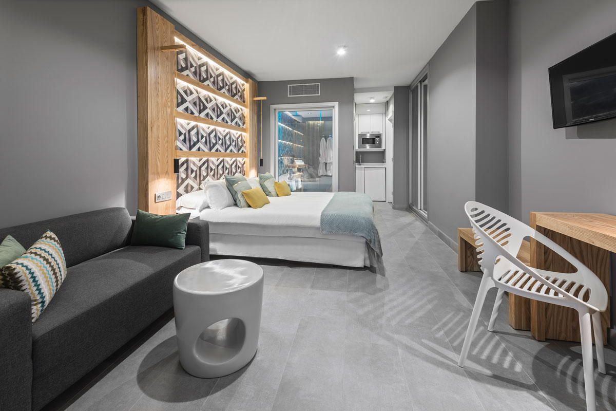 Modern hotel room with bed, sofa, and kitchenette in Tenerife.
