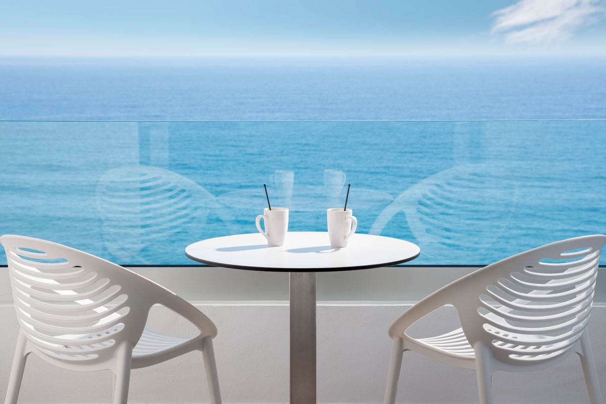 Two chairs and a table with cups overlooking the ocean in Tenerife.