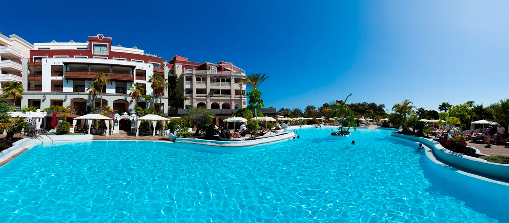Outdoor pool with people relaxing by the water at a resort in Tenerife.