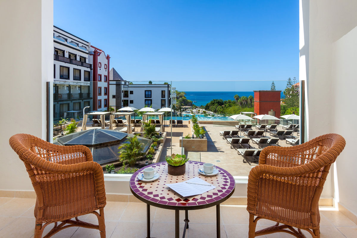 Terrace view of outdoor seating and ocean at Tenerife hotel.