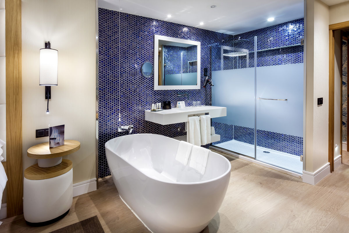 Modern bathroom with bathtub, shower, and blue tile wall in Tenerife hotel.