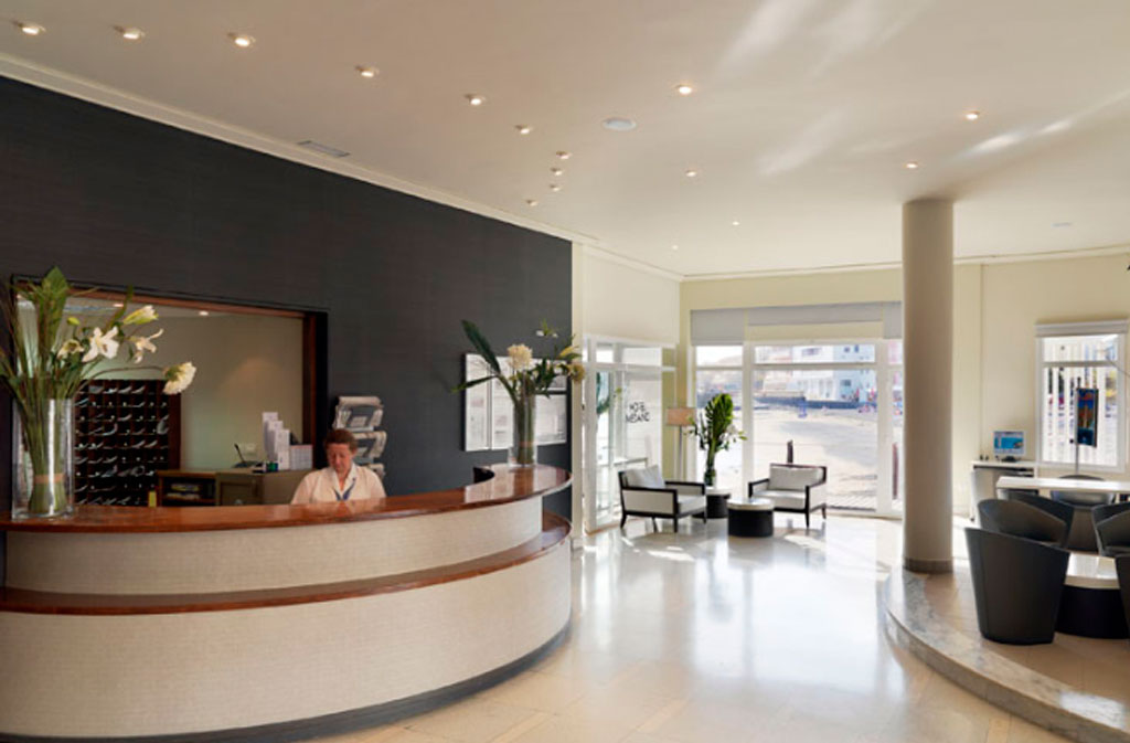 Reception desk with a woman working, flowers, and seating area in a hotel in Tenerife.