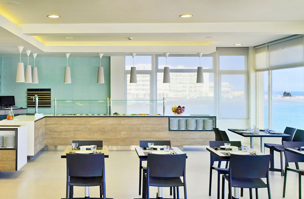 Dining area with tables and chairs at a restaurant in Tenerife with ocean view.