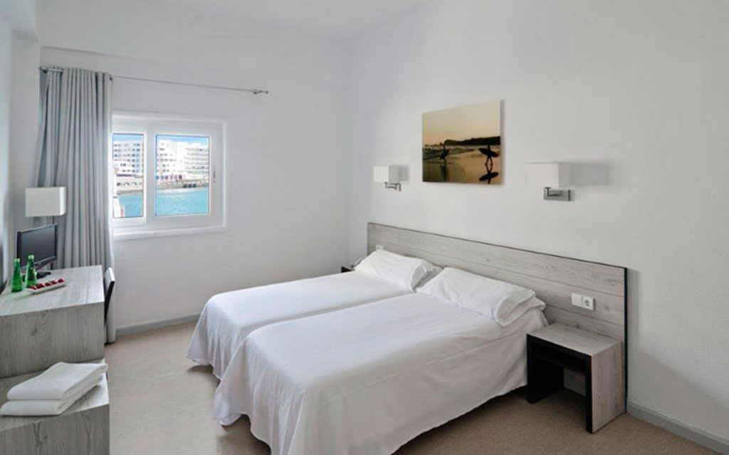 Twin beds in a Puerto de la Cruz hotel room with a window view.
