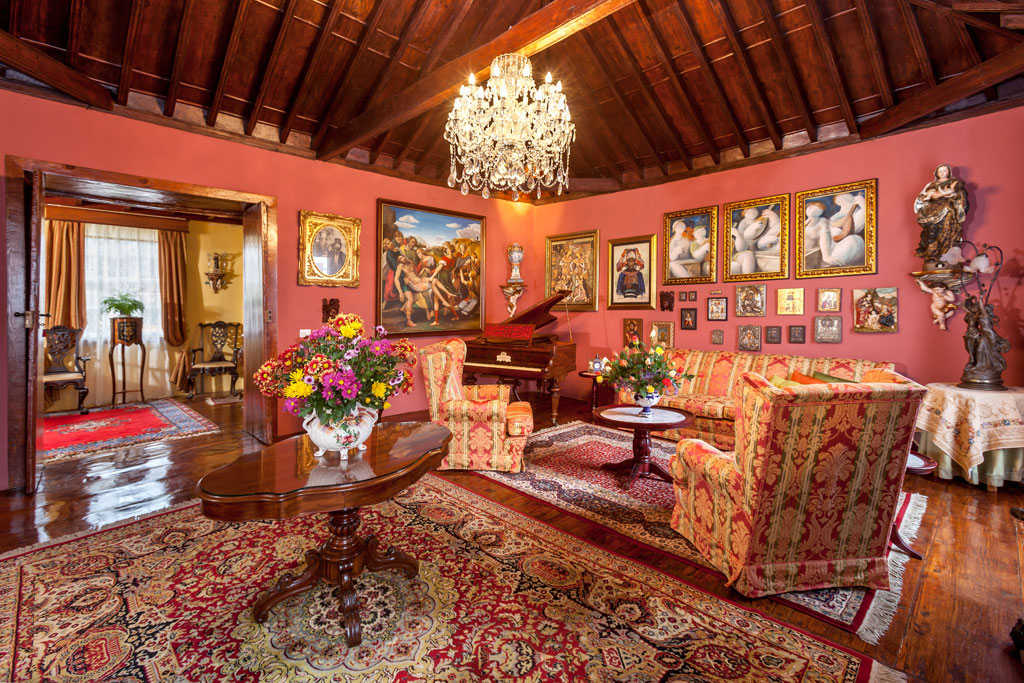 Luxurious living room in Tenerife with red walls, chandelier, and art paintings.