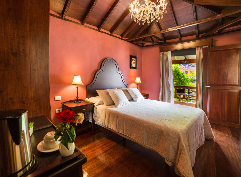 Bedroom with double bed, chandelier, and balcony view in Tenerife.