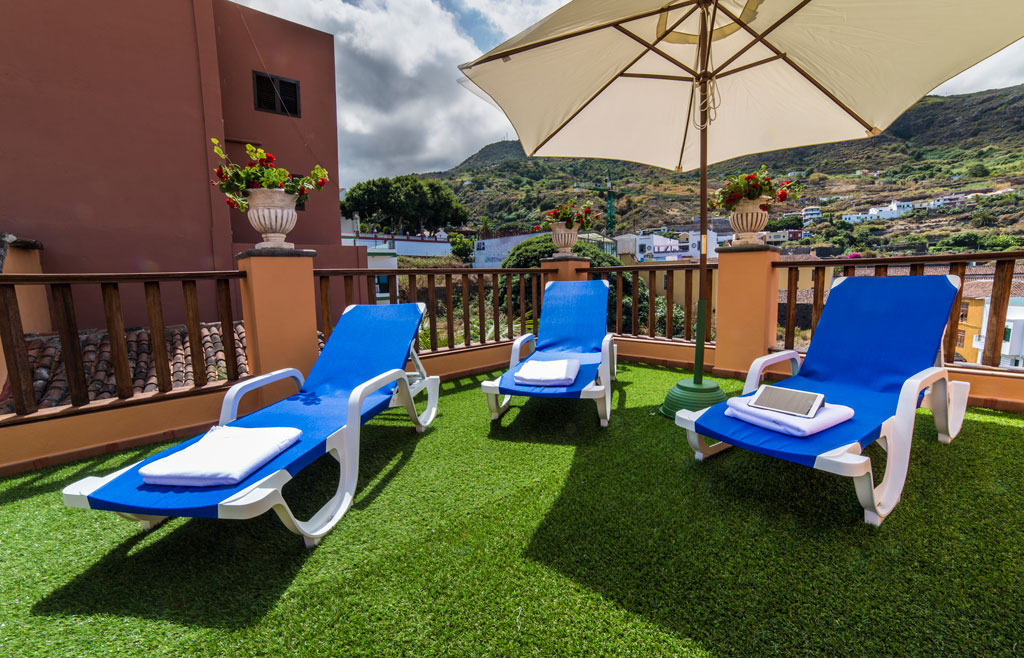 Three blue sun loungers with towels and umbrella on a terrace in Tenerife.