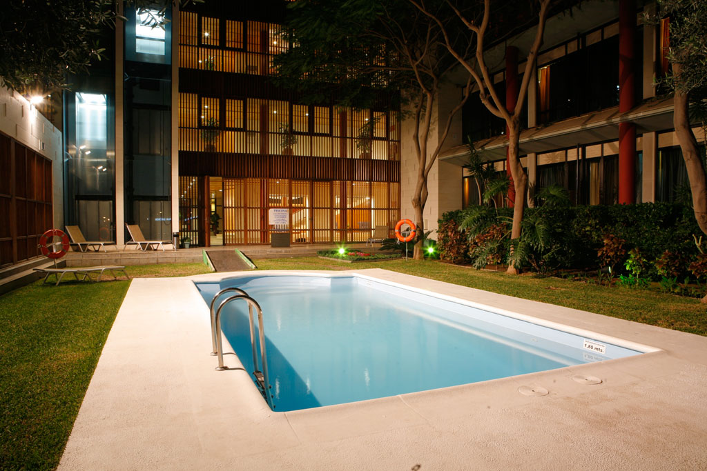 Outdoor pool at night surrounded by greenery in a Tenerife hotel courtyard.