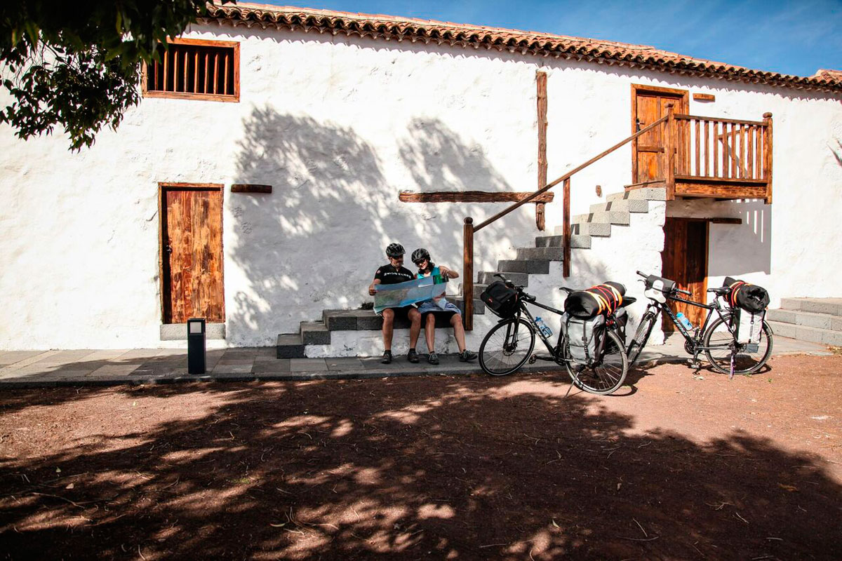 Two cyclists resting with a map in front of a building in Tenerife.