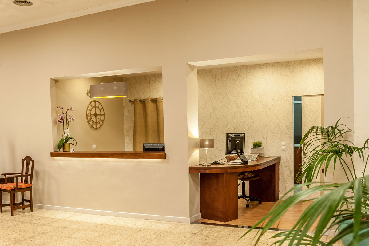 Hotel reception desk area in Tenerife with computer and orchids.