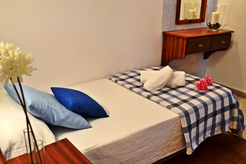 Single bed with blue plaid blanket, pillows, and towels in a Tenerife room.