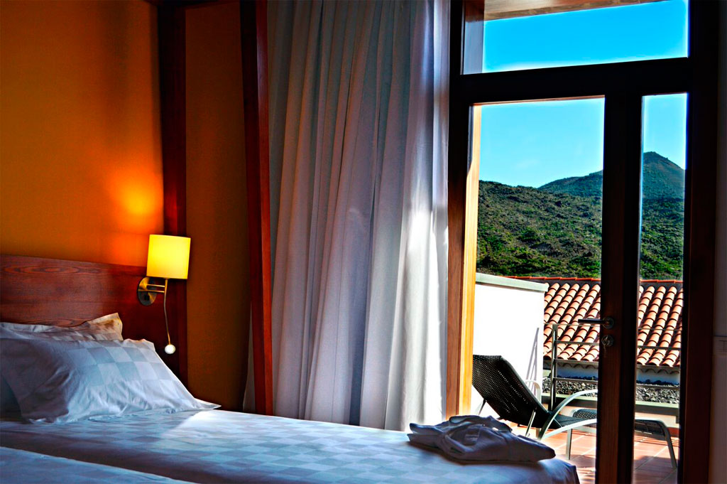 Room with bed and lamp, view of mountains and terrace in Tenerife.