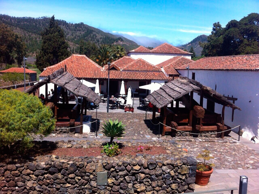 Courtyard with stone path, wooden structures, and red-tile roofs in Tenerife.