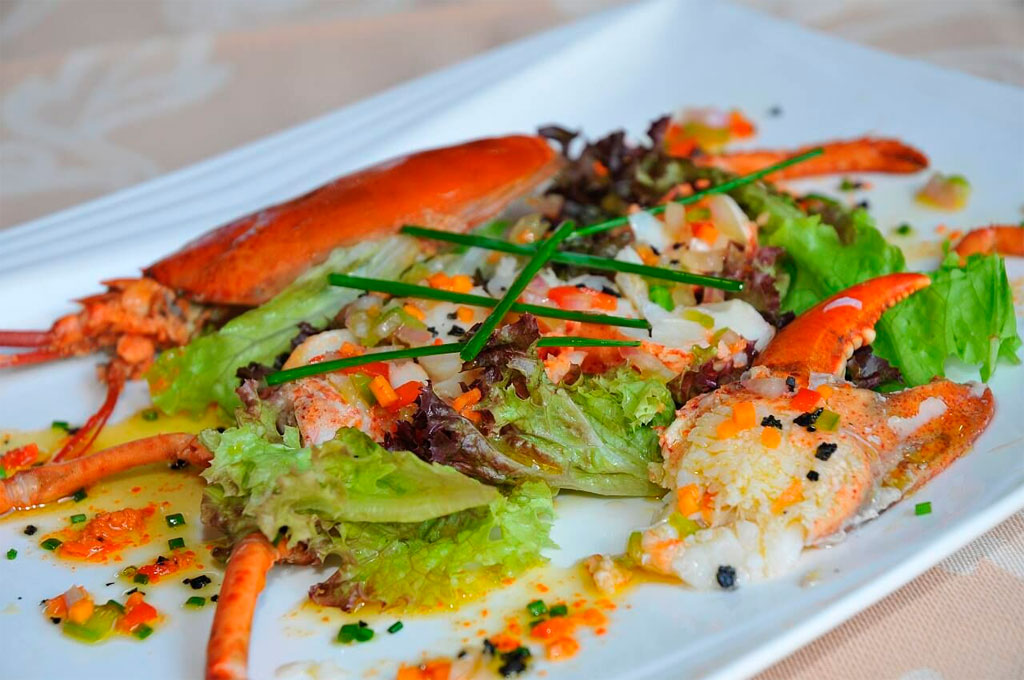 Lobster salad garnished with chives and mixed greens on a white plate, Tenerife.