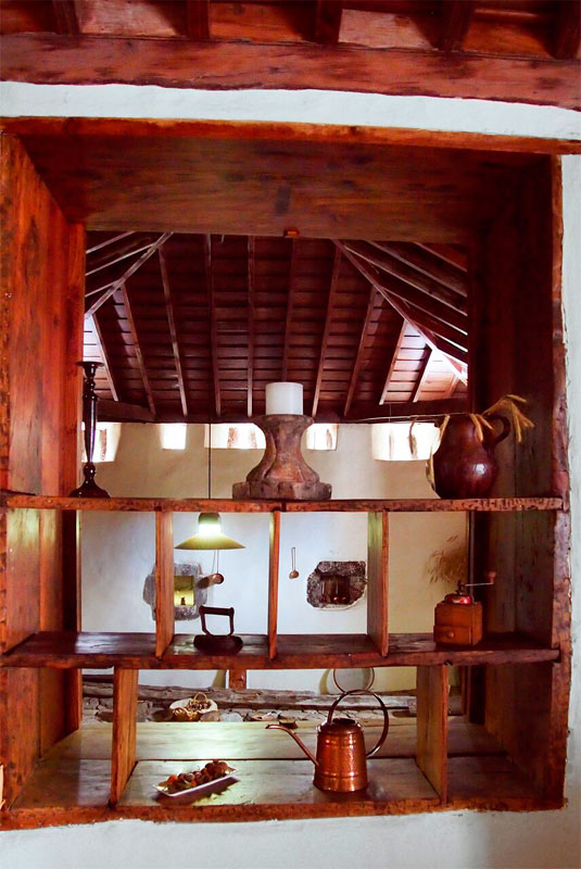 Wooden shelf with candles, pots, and decor items in a rustic room in Tenerife.