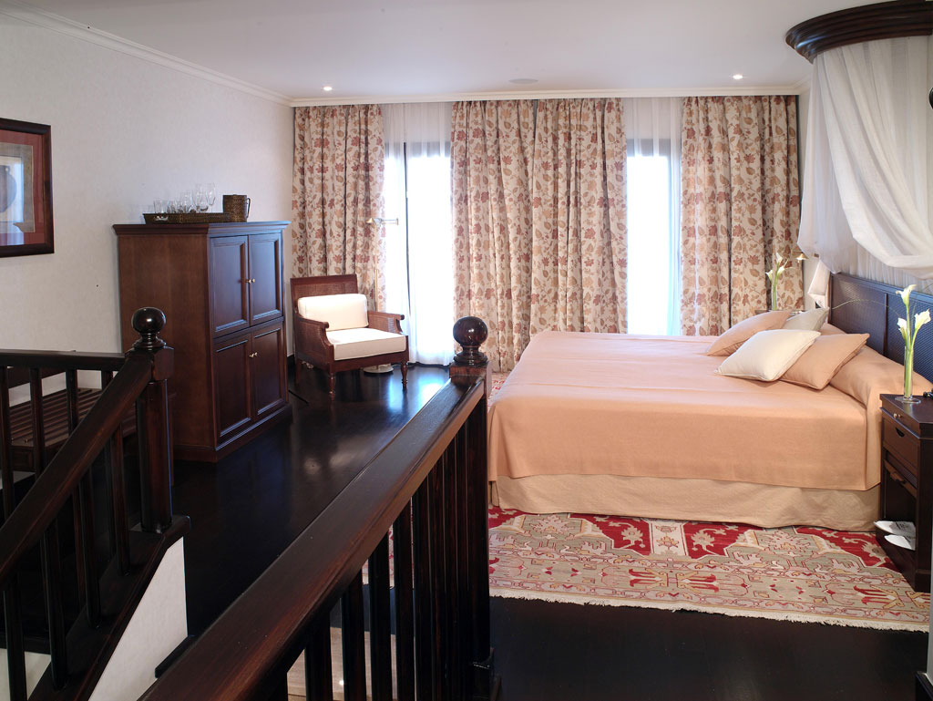 Bedroom with wooden furniture and floral curtains in a Tenerife hotel room.