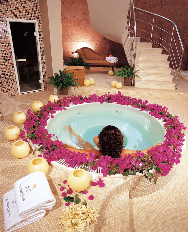 Person relaxing in a jacuzzi surrounded by pink flowers at Las Madrigueras, Tenerife.