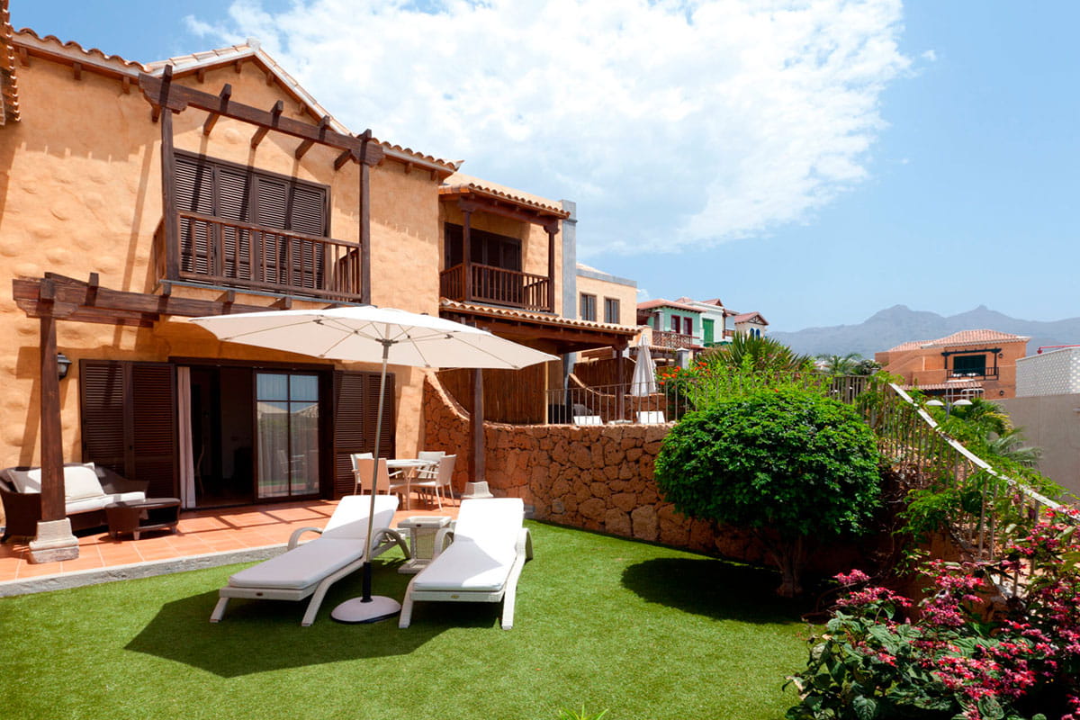 Terrace with loungers and umbrella in a garden at a Tenerife villa.