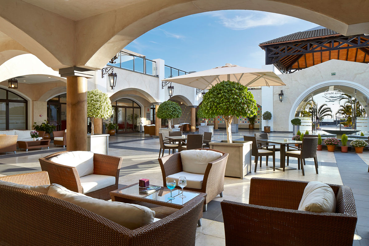 Outdoor seating area with wicker furniture and umbrellas at a hotel in Tenerife.
