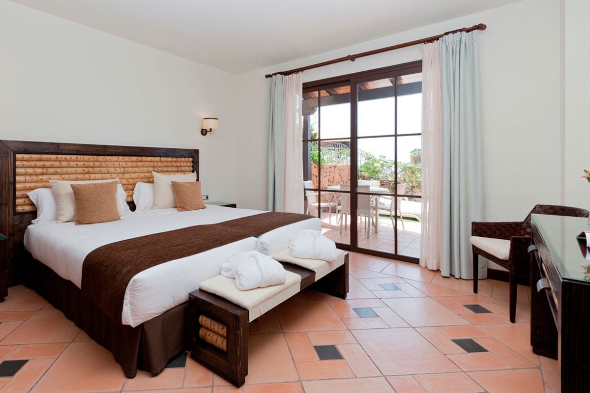 Modern bedroom with a large bed and patio doors overlooking a garden in Tenerife.