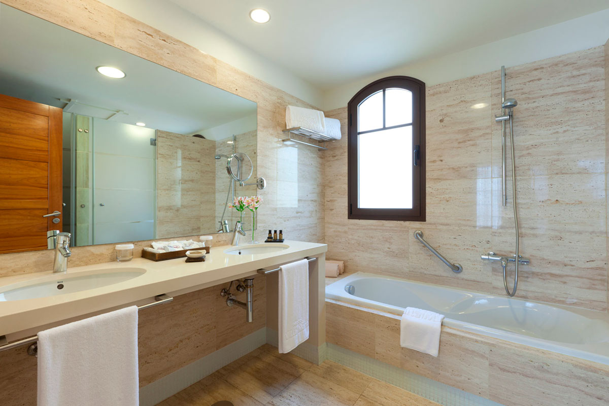 Bathroom with mirror, sink, bathtub, shower, and window in a Tenerife hotel.