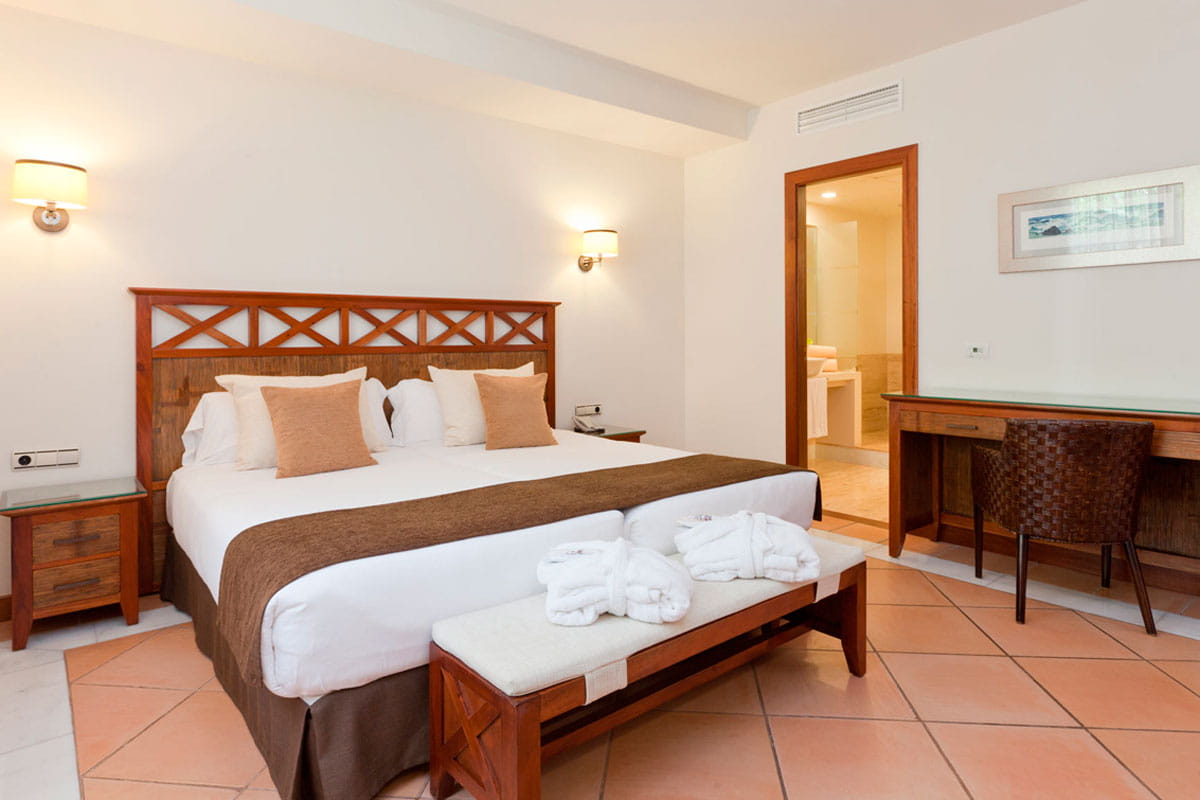 Bedroom with double bed, desk, and open door to bathroom in Tenerife hotel.