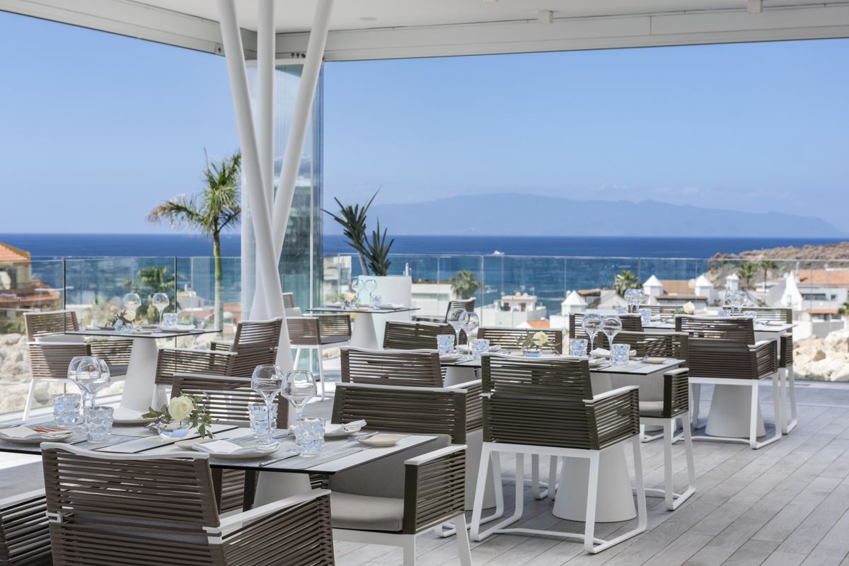 Outdoor dining area with ocean view in Tenerife, featuring set tables and chairs.