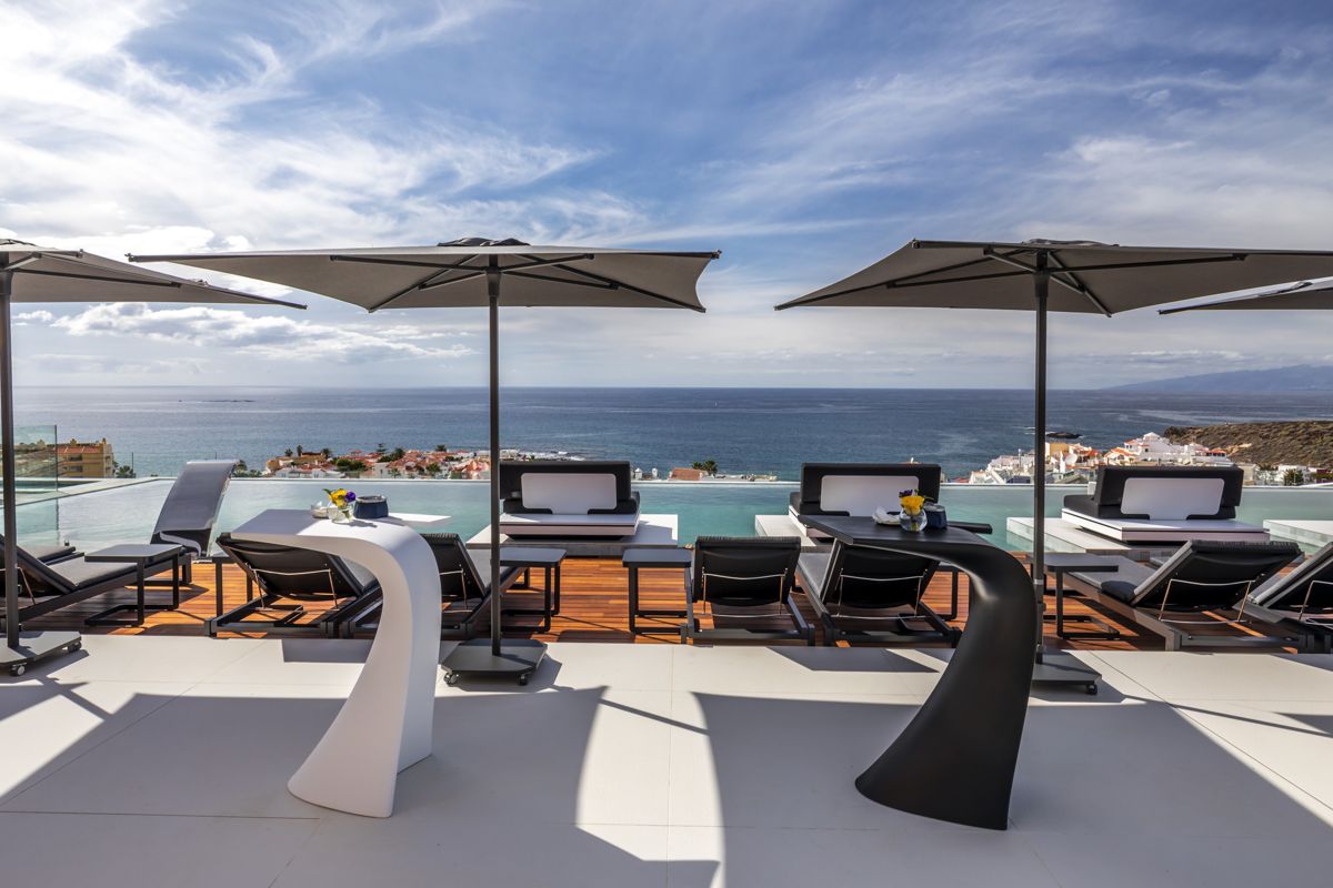 Rooftop terrace with loungers and umbrellas overlooking the ocean in Tenerife.