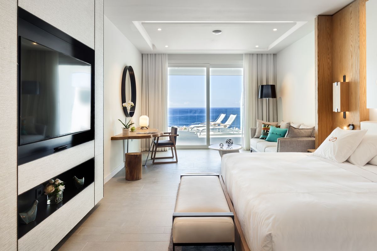Hotel room with sea view in Tenerife, featuring a bed, TV, and seating area.