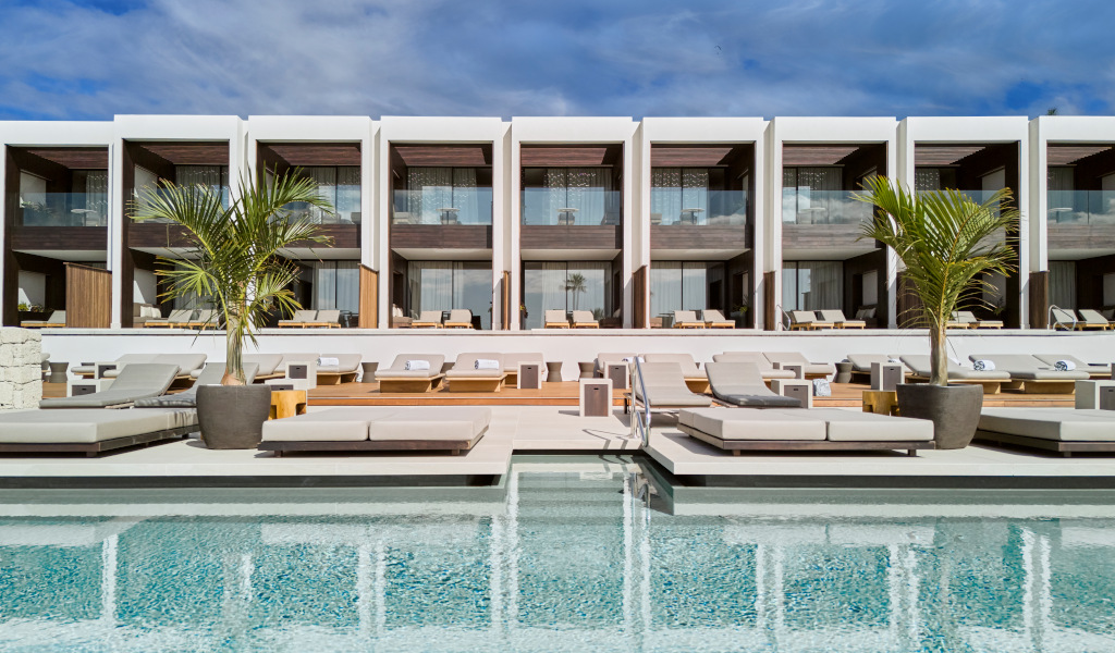 Outdoor pool area with sun loungers and modern building in Tenerife.