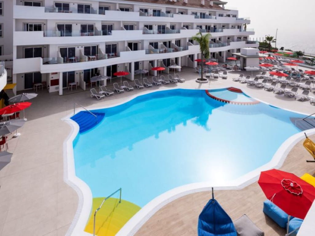 Swimming pool surrounded by sun loungers and parasols in a tourist complex in Tenerife.