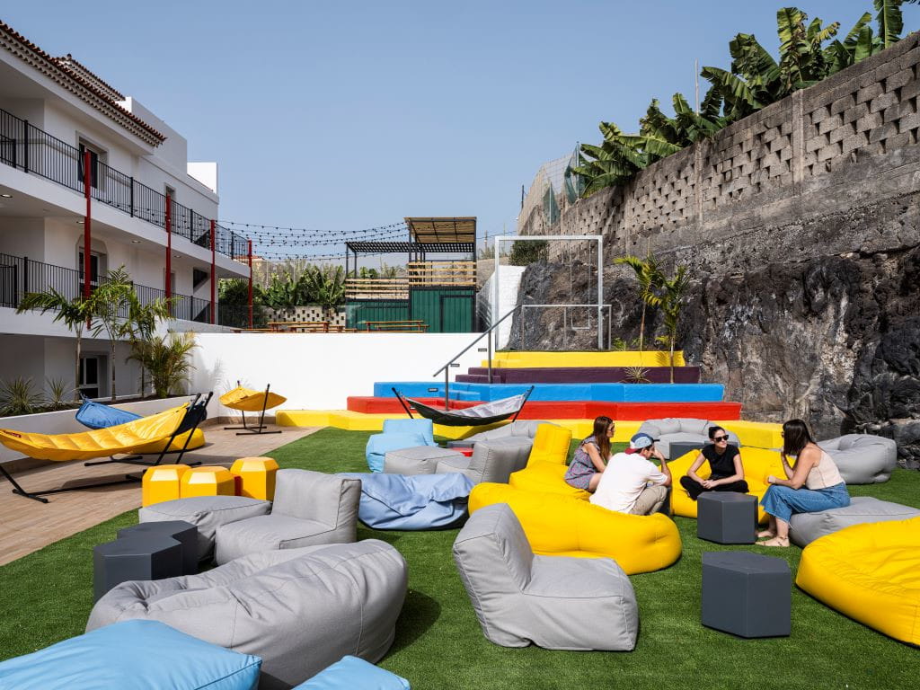 People chat in outdoor space with hammocks and colorful bean bags in Tenerife.