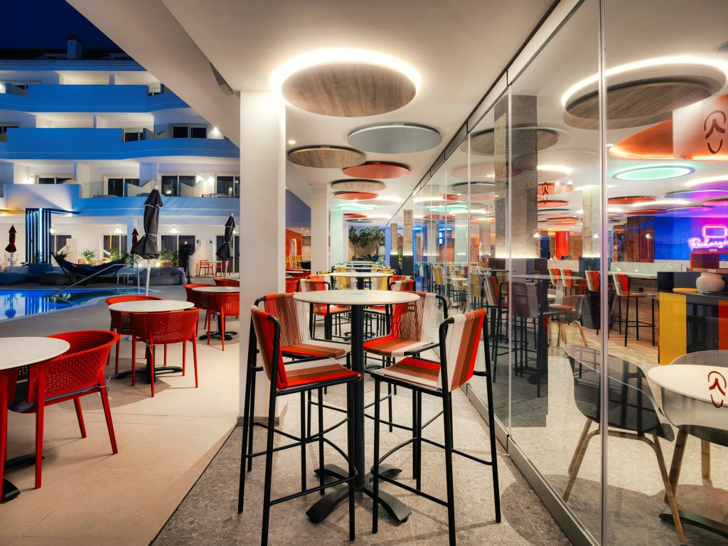 Terrace of a restaurant with red tables and chairs in a hotel in Tenerife at night.