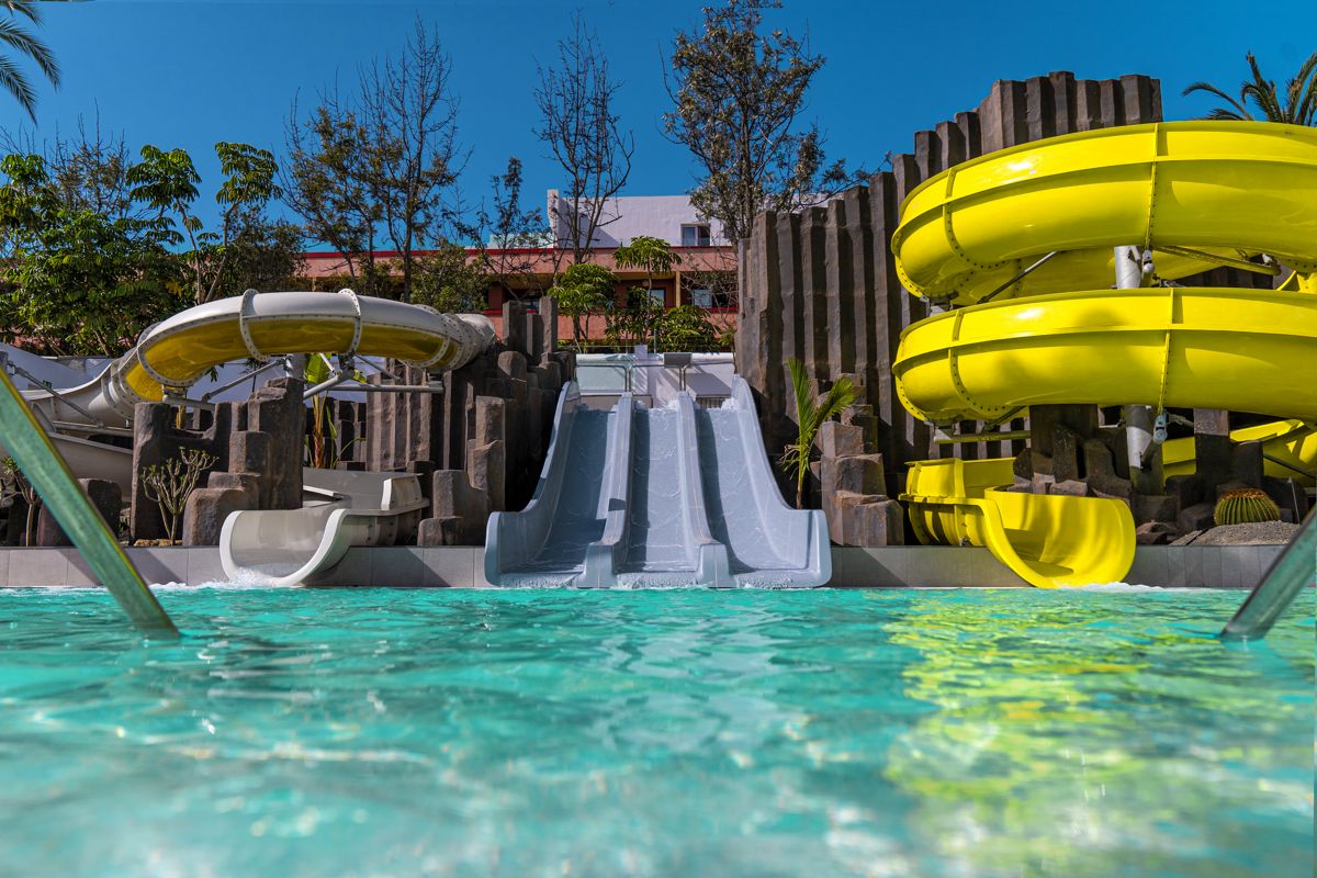 Water slides leading into a pool at a Tenerife water park.
