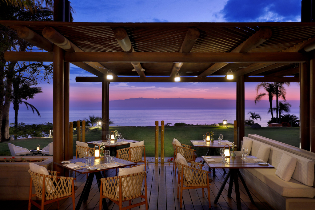 Outdoor dining area with tables and ocean view at sunset in Tenerife.
