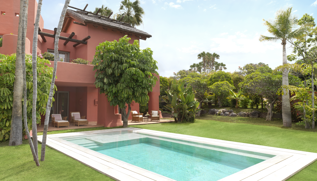 Pool and garden near a red villa in Tenerife.