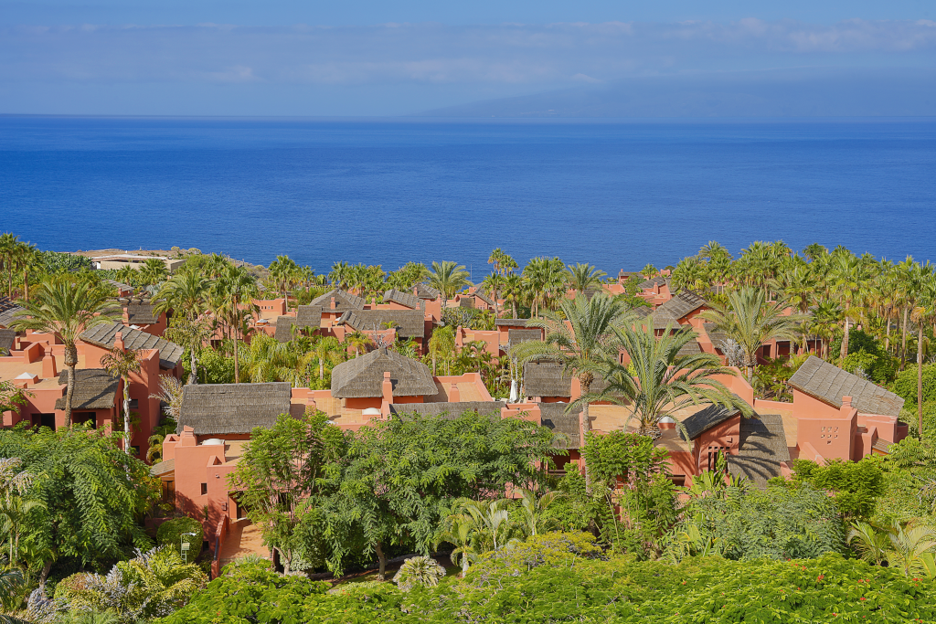 Terracotta villas surrounded by palm trees with ocean view in Tenerife.
