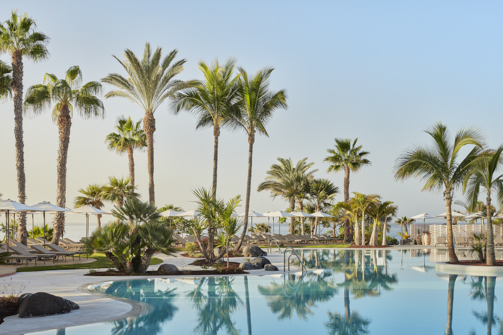 Swimming pool surrounded by palm trees at a Tenerife resort.