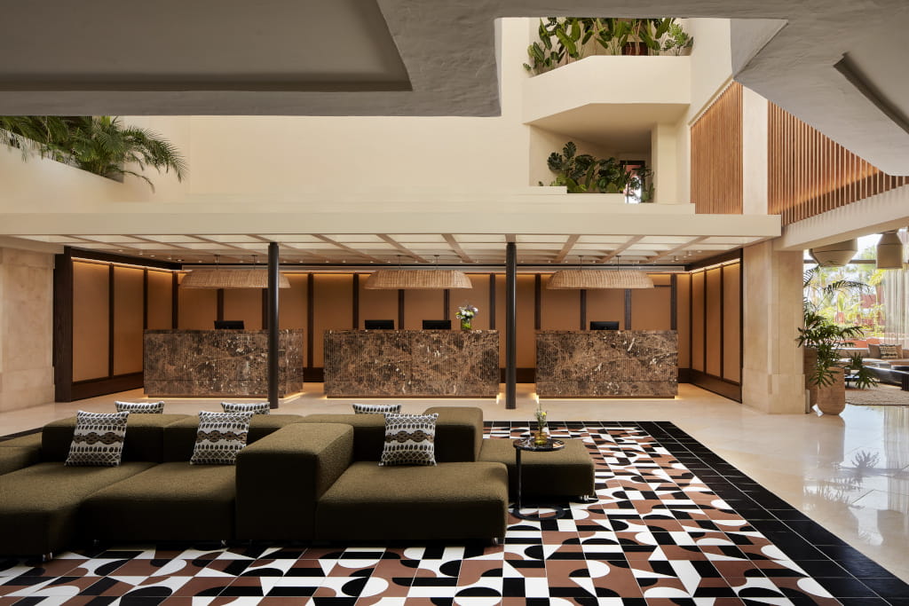 Lobby with patterned floor and brown reception desks, green plants in Tenerife.