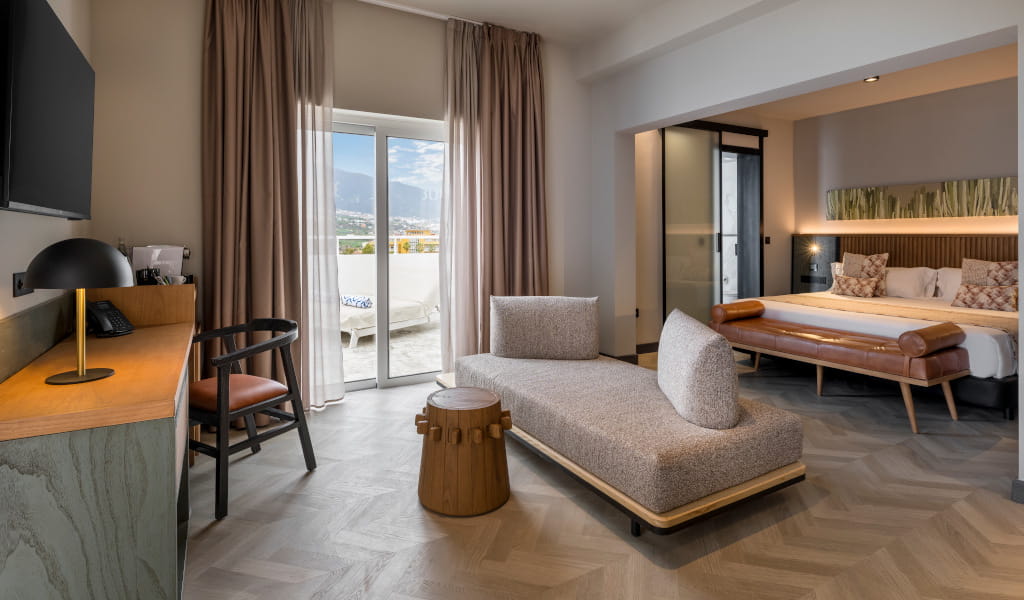 Modern hotel room in Tenerife with a bed, desk, and seating area.