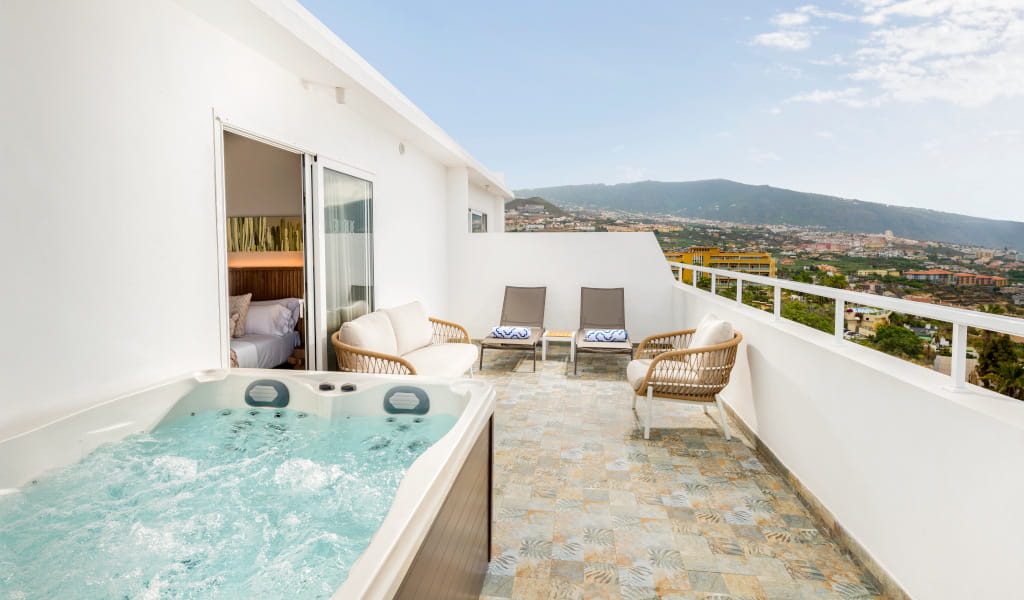 Private terrace with jacuzzi and lounge chairs overlooking Puerto de la Cruz in Tenerife.