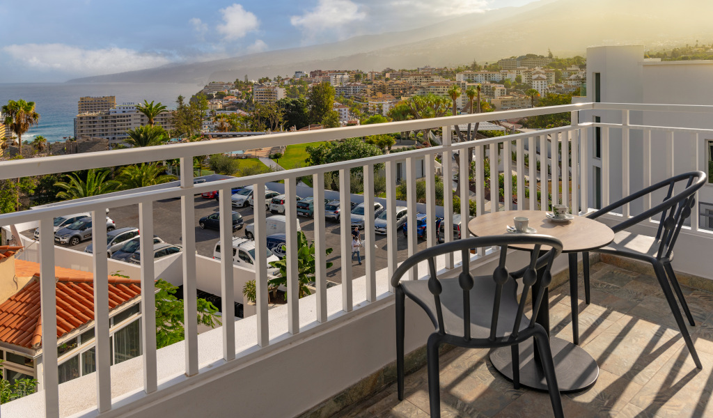 Balcony with chairs and table overlooking Puerto de la Cruz, Tenerife, ocean and city view.