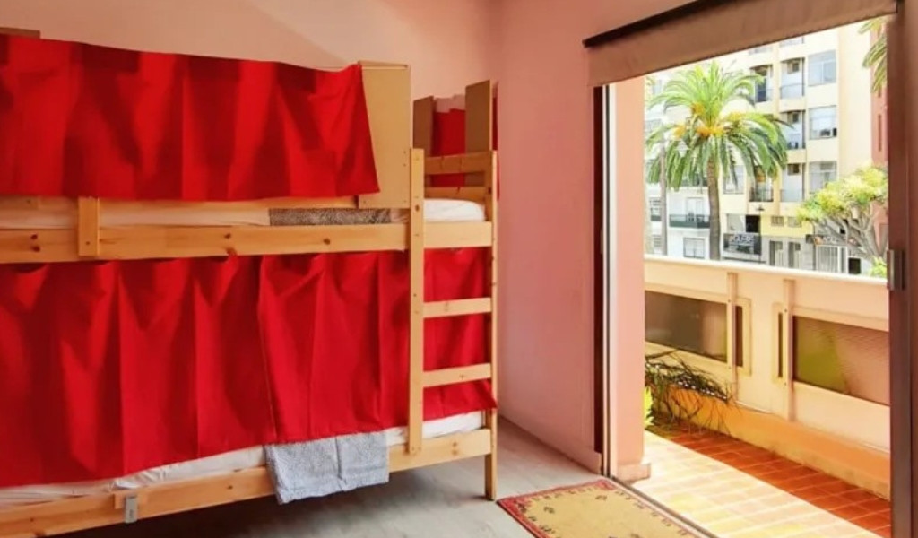 Bunk bed with red curtains beside a balcony, Santa Cruz de Tenerife.