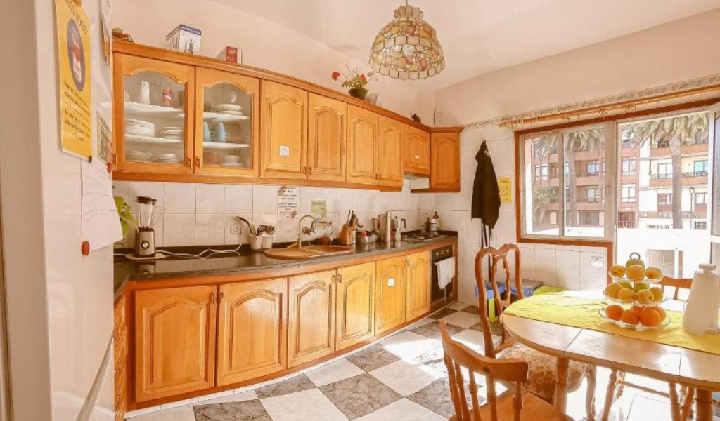 Kitchen with wooden cabinets, table with fruit bowl, and window in Santa Cruz de Tenerife.