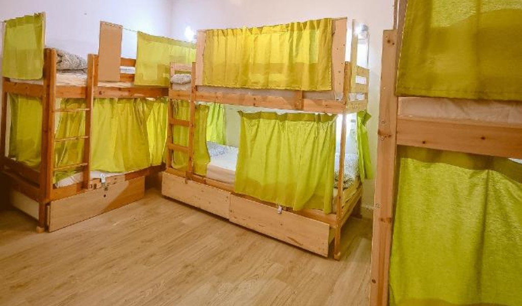 Room with wooden bunk beds and green curtains in Tenerife hostel.