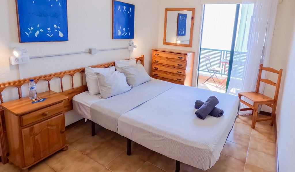 Bedroom with twin beds, wooden furniture, and a small balcony in Tenerife.