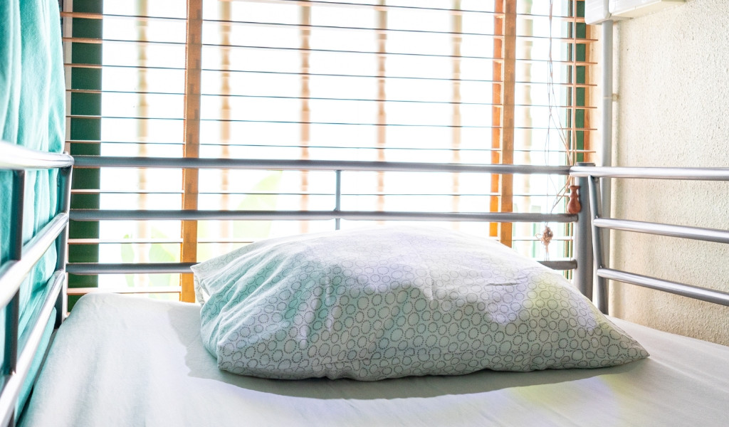 Pillow on a metal bed frame near window blinds in Tenerife.