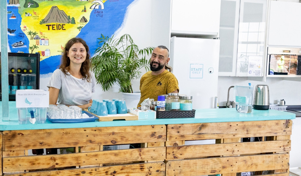 Man and woman behind counter with blue cups and map of Tenerife.