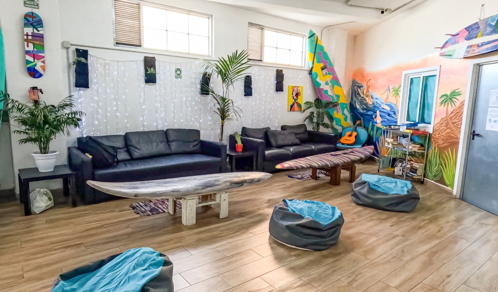 Lounge area with sofas, surfboards, guitar, and plants in Tenerife room.