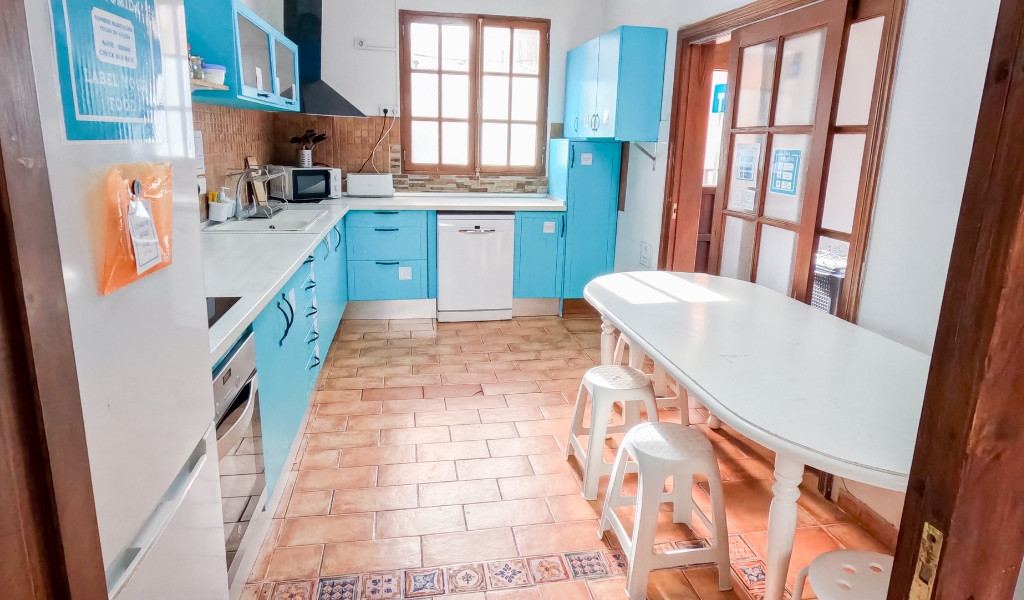 Kitchen with blue cabinets, white table, stools, and window in Tenerife.